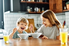 Image Two healthy children eating yogurt and smiling.