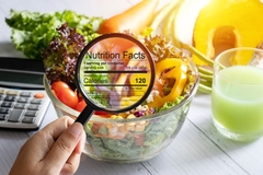 nutrition data inside magnifying glass held over a bowl of vegetable and fruit