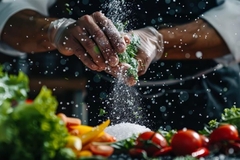 A chef using salt on vegetables.