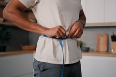 Man who lost weight and measures his waist.