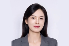 Image A woman with dark hair wearing a grey suit