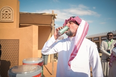 Image an Arab man drinking cola from a green can.
