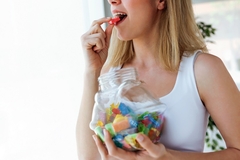 Image A woman eating red candy.