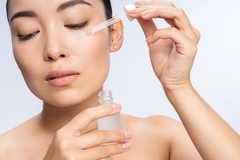 Image A woman putting a serum on her cheek.