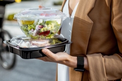 Image Woman holding food in takeaway packaging.