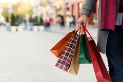 man holding paper shopping bag in street