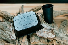 A black container on wood chips.