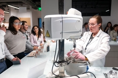 Image A scientist showing a machine off to onlookers.