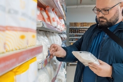 Image Overweight man reading product label in a supermarket.