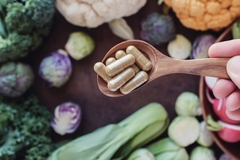 Image A spoon with supplements over vegetables.