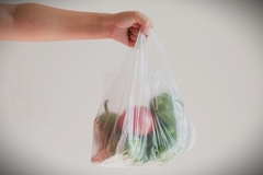 Image Holding single-use plastic bag with apples.