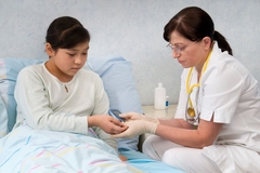 doctor checks blood sugar of young girl in bed