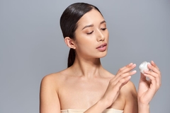 Image A woman holding a pot of moisturizer.