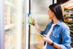 Image A shopper examining frozen foods.