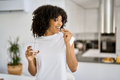 Image Woman taking supplement tablet