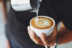 Image Barista adding milk to coffee