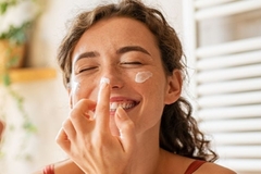 Image A woman touching her nose with moisturizer on it.