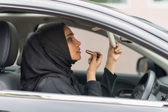 Image Woman in hijab putting on lipstick in car mirror