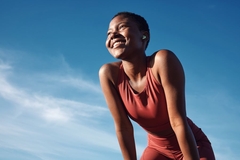 Image fit woman in gym clothes under blue sky smiling