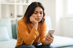 Image woman looking at phone depressed.