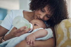 Image mother hug and feeds baby with bottle