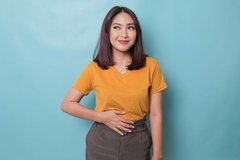 A young woman smiles while holding her stomache and feeling full and satisfied.