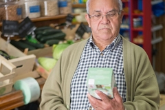 Image elderly man looks at food label