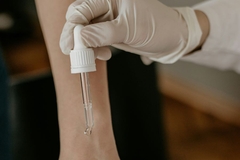 A hand depositing an oil on someones arm.