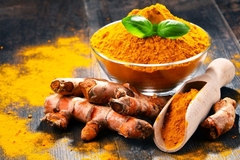 Image Turmeric on a table in a pestle with turmeric root surrounding it.