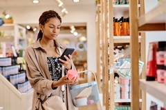 Image A woman scanning a beauty product with her phone in a store.