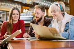 Image three young adults reading restaurant menus