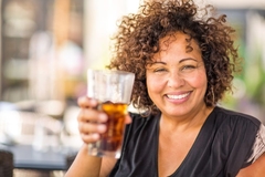 Latina woman smiling with a soda.