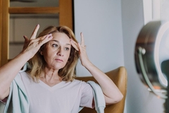 Image Woman looking at aging skin in the mirror