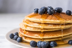 Image Pancakes on a plate with syrup and blueberries.