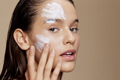 A woman with large swipes of face cream on her cheek.