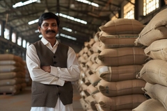 Indian farmer in warehouse filled with grain bags