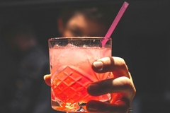 Man holding drink with plastic straw.