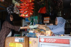 Image woman in cramped kiosk hands woman bottle for refill