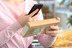 A person holding a box and a phone.
