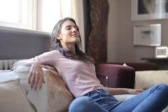 Image A woman relaxes by laying back on a couch.