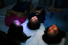 Image Girls on their phones in a dark room
