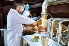 Image a mature scientist brewing beer in a fermenter