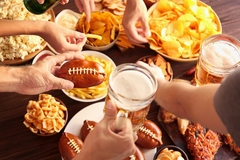 Image People eating several unhealthy snacks and drinking beers while watching the Super Bowl.