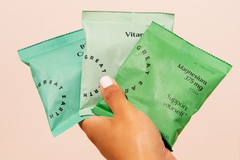 hand holding four green refill packages