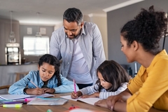 Image Parents help their adolescent children do their homework at the kitchen table.