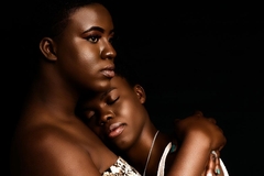 Image Two Black women embracing with shiny makeup on their bodies.