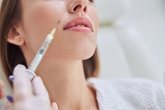 A woman getting a needle above her mouth.
