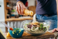 Image man pouring salad dressing over salad