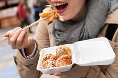 Image A person eating food with chopsticks.
