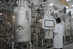 Scientist in front of fermentation tank with clip board in lab